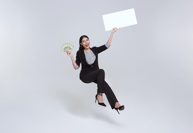 Free photo smiling confident asian businesswoman holding money banknote and blank banner floating in midair