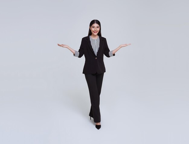 Smiling Confident Asian businesswoman with gesture of introduce isolated over gray background