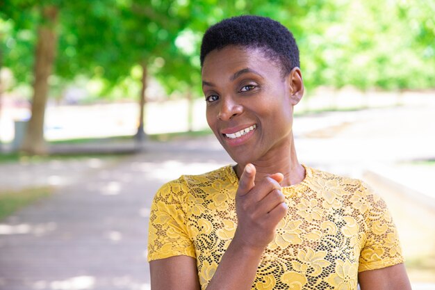 Smiling confident black woman pointing with finger at camera