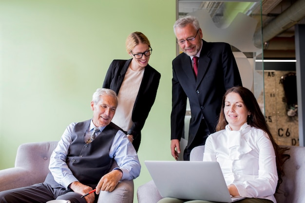 Smiling confident businesswoman showing laptop to her coworker in the office