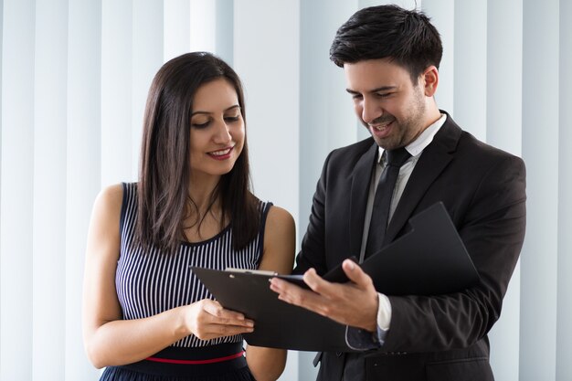 Smiling confident colleagues examining document together