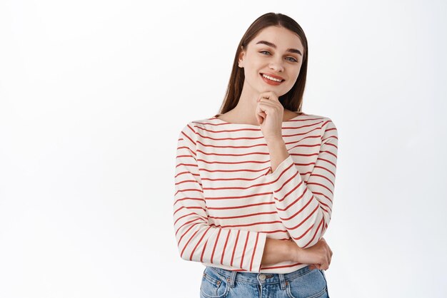 Smiling confident woman made her choice looking pleased and thoughtful touching chin as if thinking like your idea or thought standing over white background