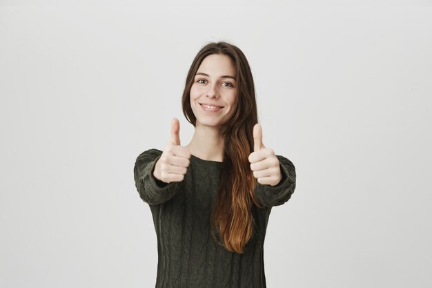 Smiling confident woman show thumbs-up, encourage or recommend