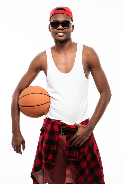 Free photo smiling confident young man standing and holding basketball ball