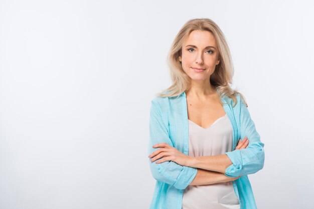 Smiling confident young woman standing with her crossed arms against white backdrop