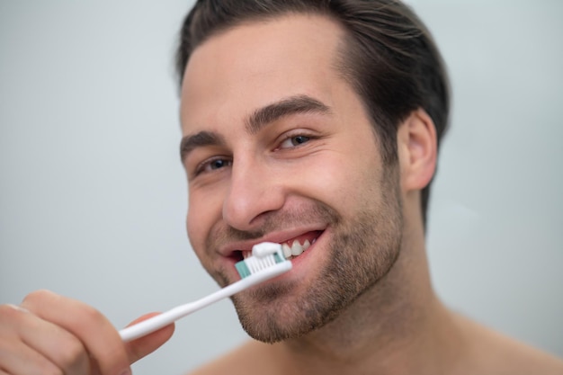 Free photo smiling contented man brushing his teeth