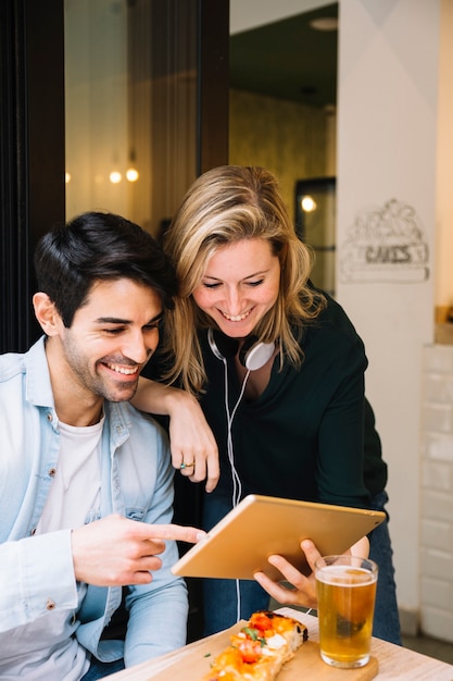 Free photo smiling couple in cafe looking at tablet