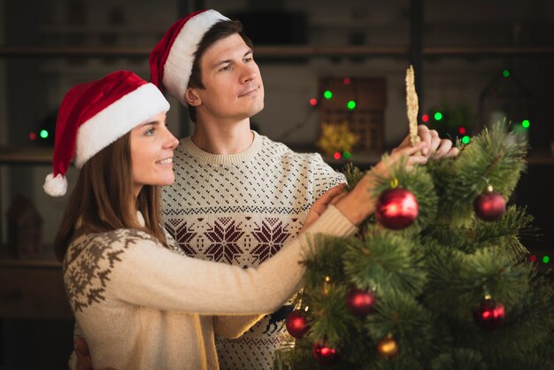 Smiling couple decorating christmas tree