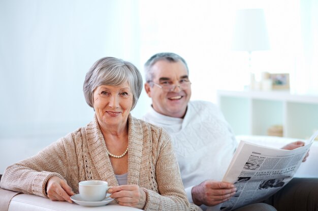 Улыбаясь пара пить кофе и читать газеты