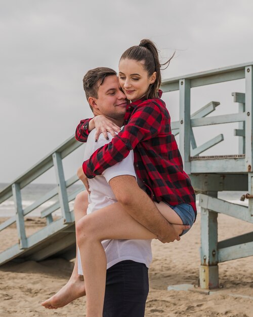 Smiling couple embraced in pose on beach