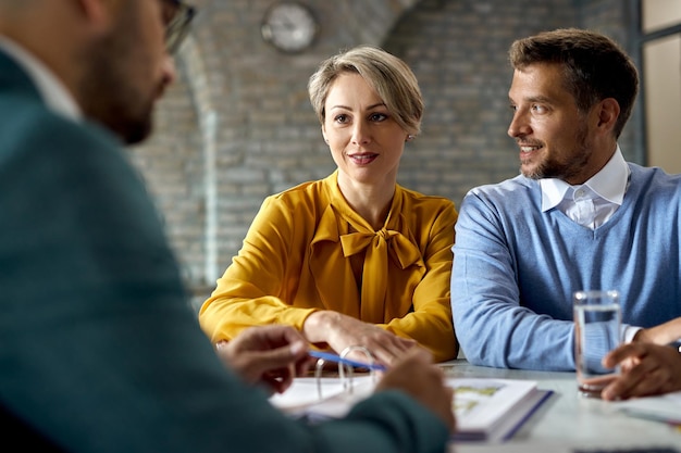 Smiling couple having consultations with their financial advisor in the office