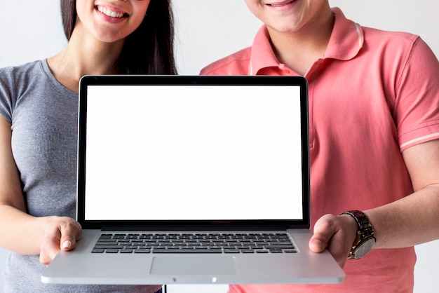 Smiling couple holding laptop showing empty white screen