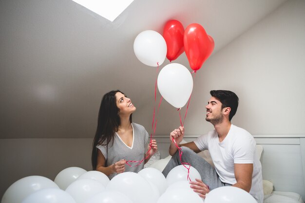 Smiling couple holding red and white balloons