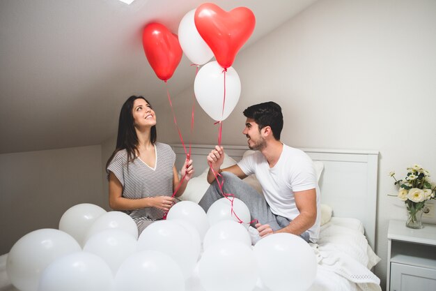 Smiling couple holding red and white balloons