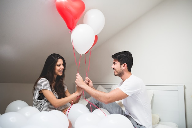 Sorridente coppia mano palloncini rossi e bianchi
