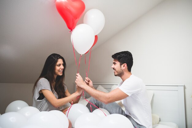 Smiling couple holding red and white balloons