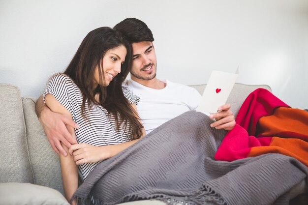 Smiling couple looking at a postcard with a heart