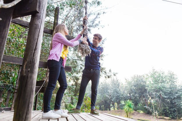 Smiling couple pulling a rope in the adventure park