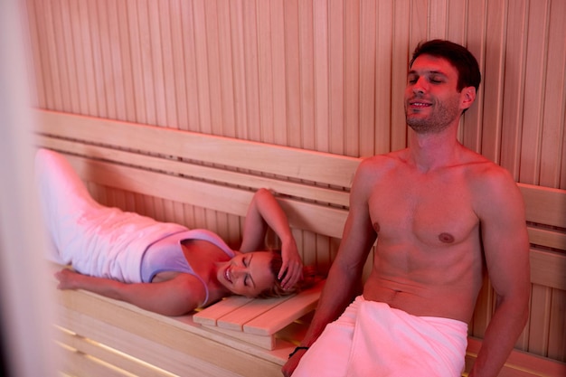 Free photo smiling couple relaxing with eyes closed in sauna at wellness center