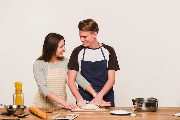 Smiling couple rolling dough together