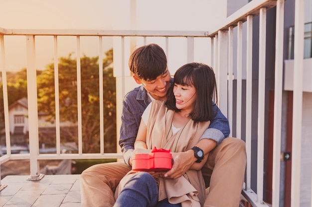 Smiling couple sitting on the floor with a red gift