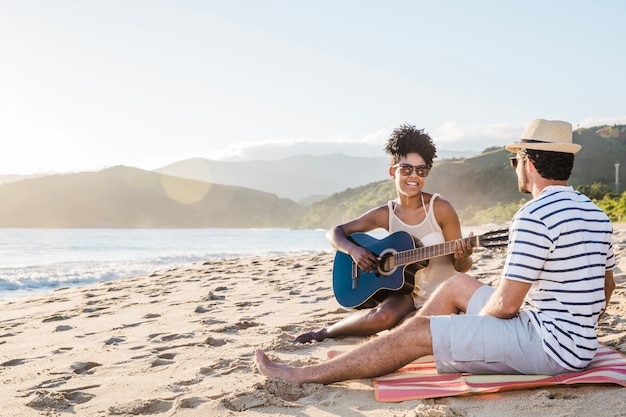 Smiling couple with guitar at the beach