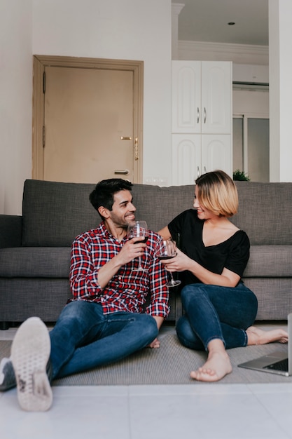 Smiling couple with wine at couch