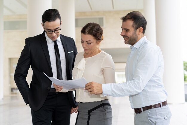 Smiling coworkers checking business documents at meeting