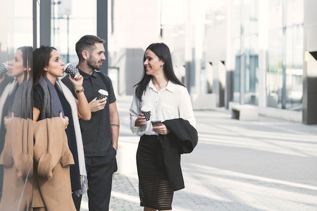 Smiling coworkers drinking coffee on street