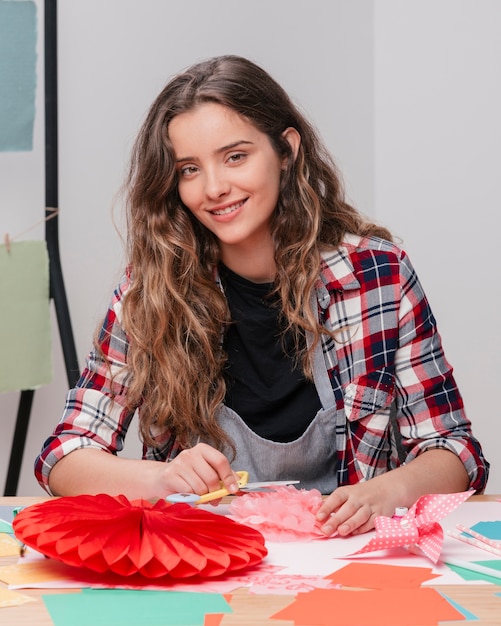 Foto gratuita artigiano sorridente che esamina macchina fotografica mentre lavorando