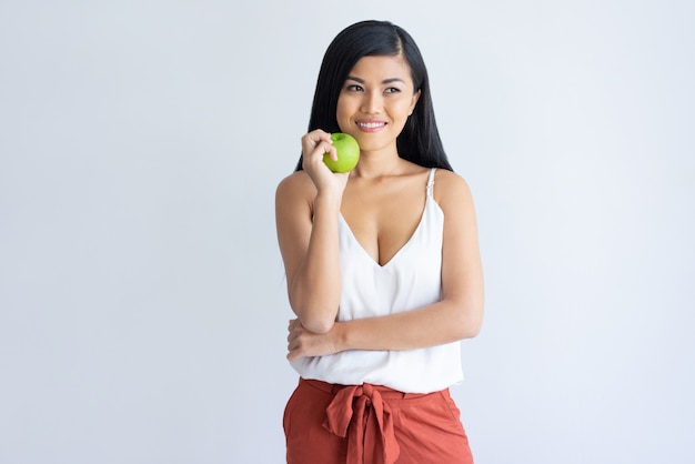 リンゴを押しながらよそ見創造的なアジアの女性の笑みを浮かべてください。