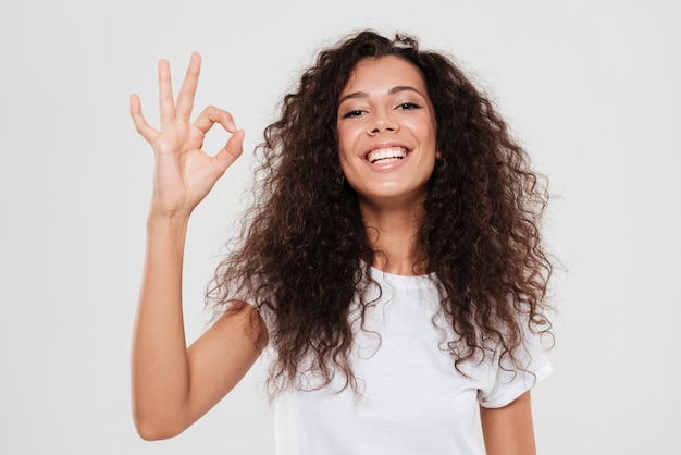 Smiling curly woman showing ok sign