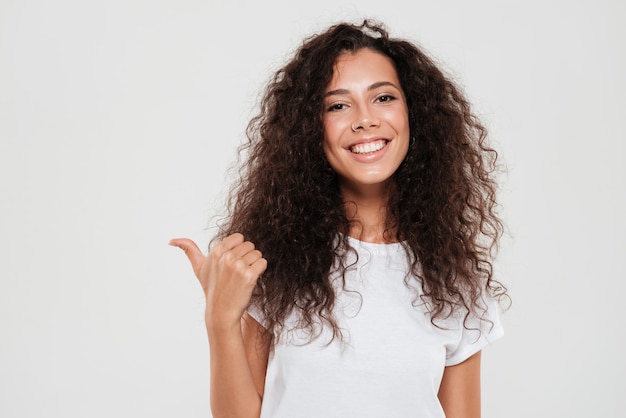 Smiling curly woman showing thumb up