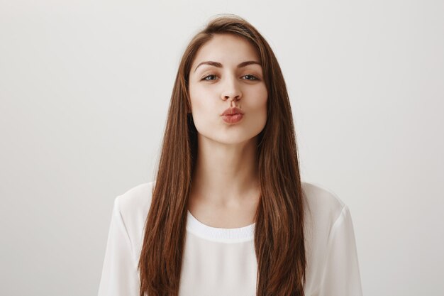 Smiling cute girl folding lips and leaning for kiss