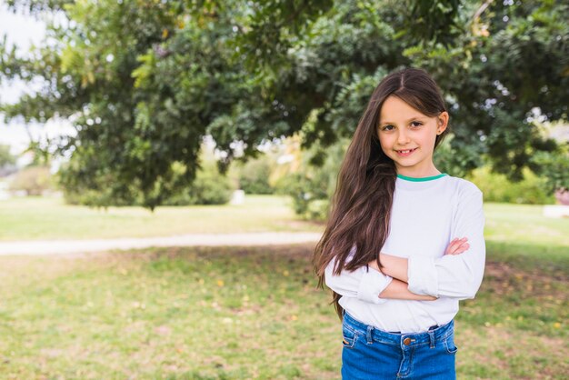 Smiling cute girl looking at camera with her arm crossed