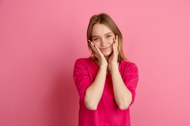 かわいい、幸せな笑顔。ピンクのスタジオで白人の若い女性の肖像画