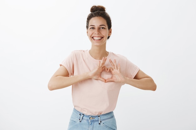 Smiling cute young stylish woman posing against the white wall