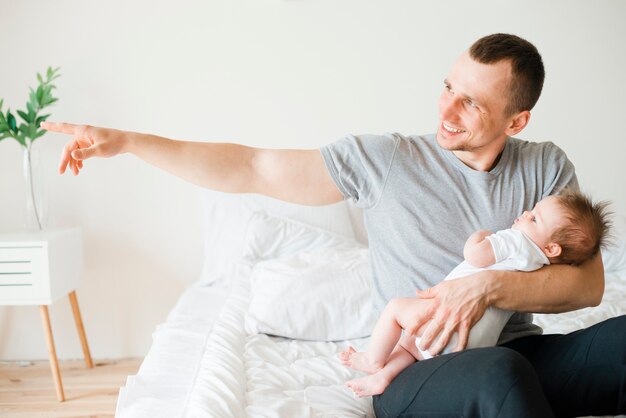 Smiling dad holding baby while pointing away