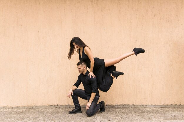 Smiling dancing woman jumping over the man's shoulder