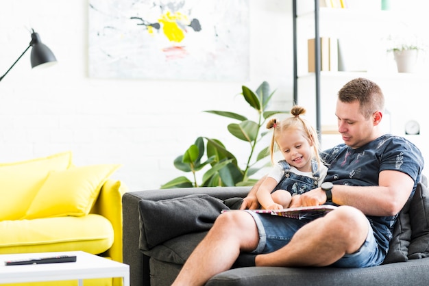 Smiling daughter and father looking in book