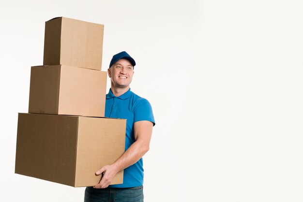 Smiling delivery man holding cardboard boxes with copy space