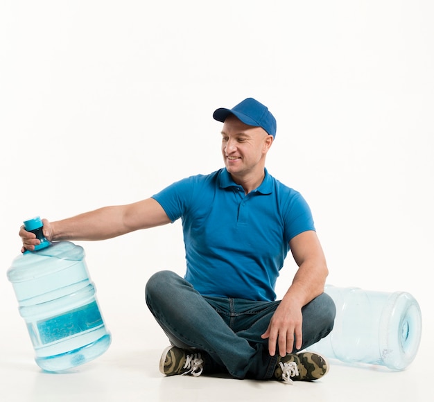 Smiling delivery man looking at water bottle