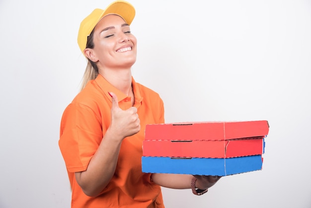 Donna sorridente di consegna tenendo le scatole per pizza su sfondo bianco.