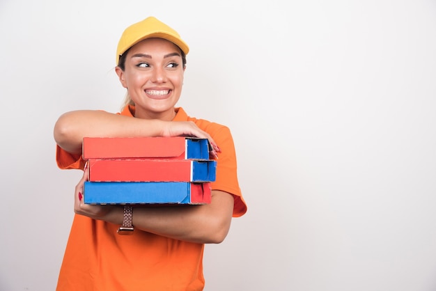 Smiling delivery woman holding pizza boxes on white background. 