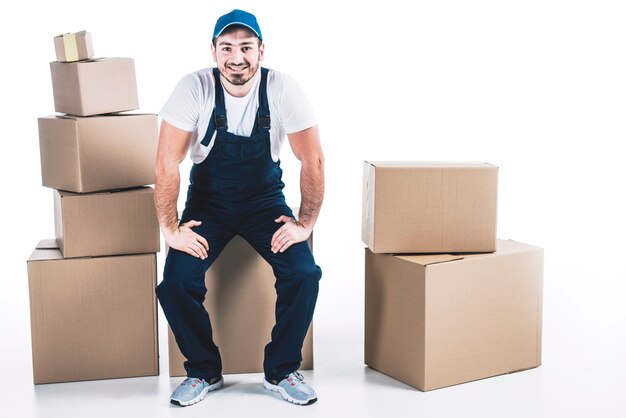 Smiling deliveryman near carton boxes