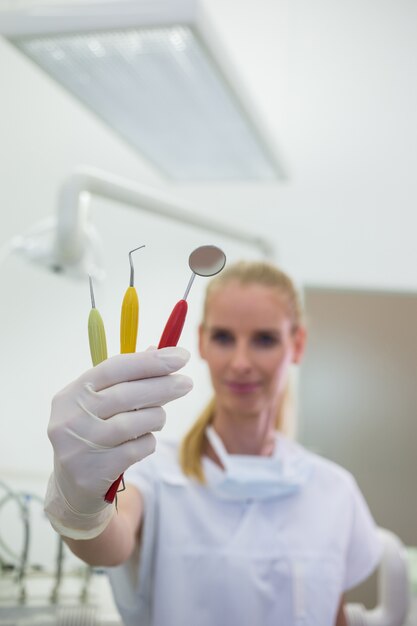 Smiling dentist holding dental tools