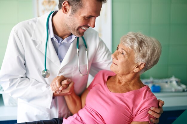 Smiling doctor helping of senior woman