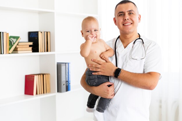 Smiling doctor holding adorable little baby