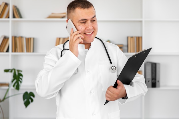 Smiling doctor holding a clipboard and talking on phone