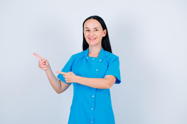 Smiling doctor is pointing left with forefingers on white background